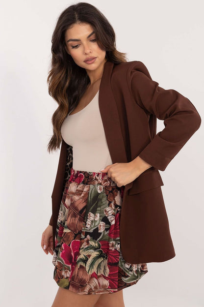 Een vrouw draagt een stijlvolle minirok met bomber snit en bloemenprint, perfect voor een casual zomerlook, beige  t-shirt met een bruine blazer, beige achtergrond,