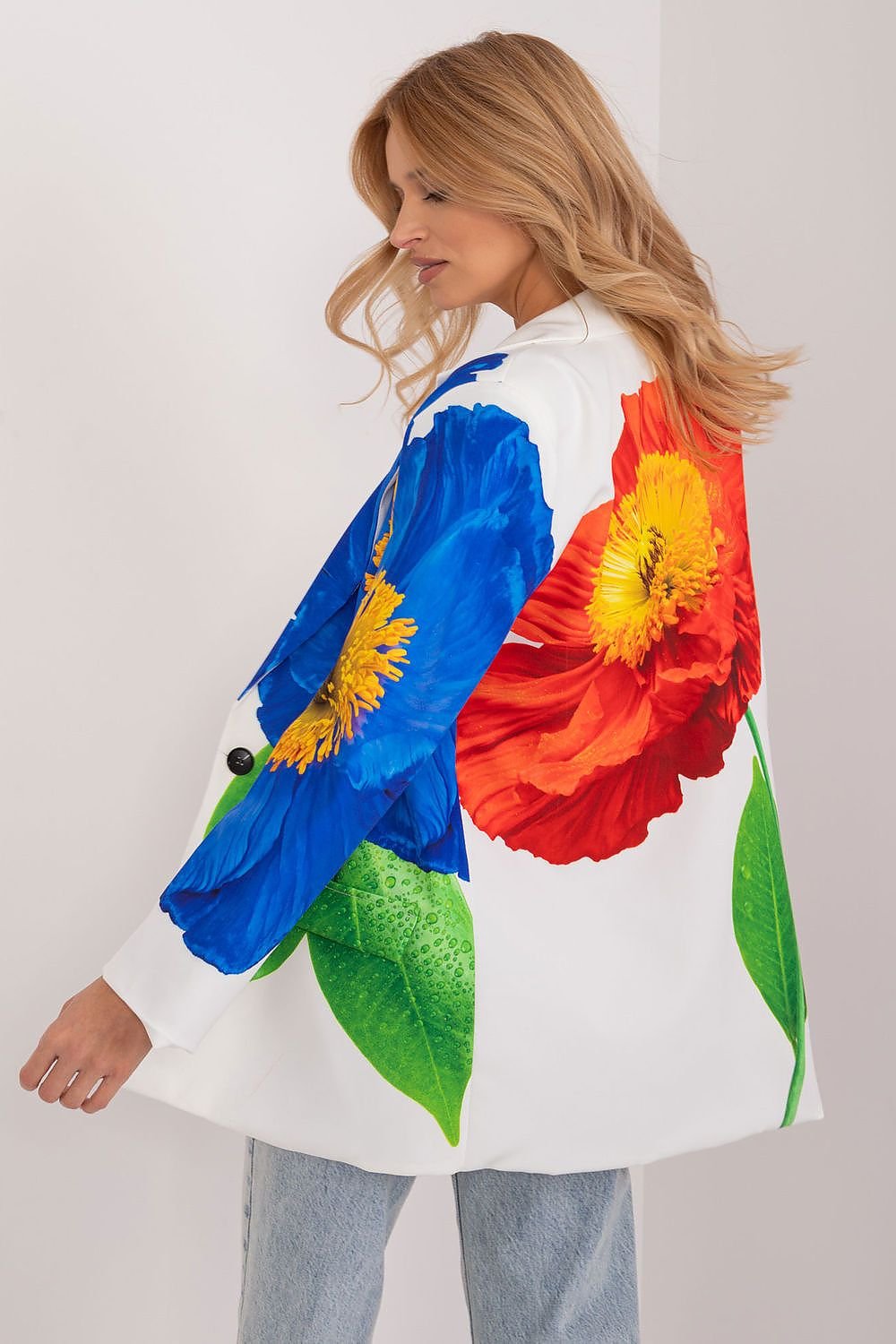 Achteraanzicht van een witte blazer met een opvallende grote bloemenprint in rood, blauw en groen, gedragen door een vrouw met jeans.