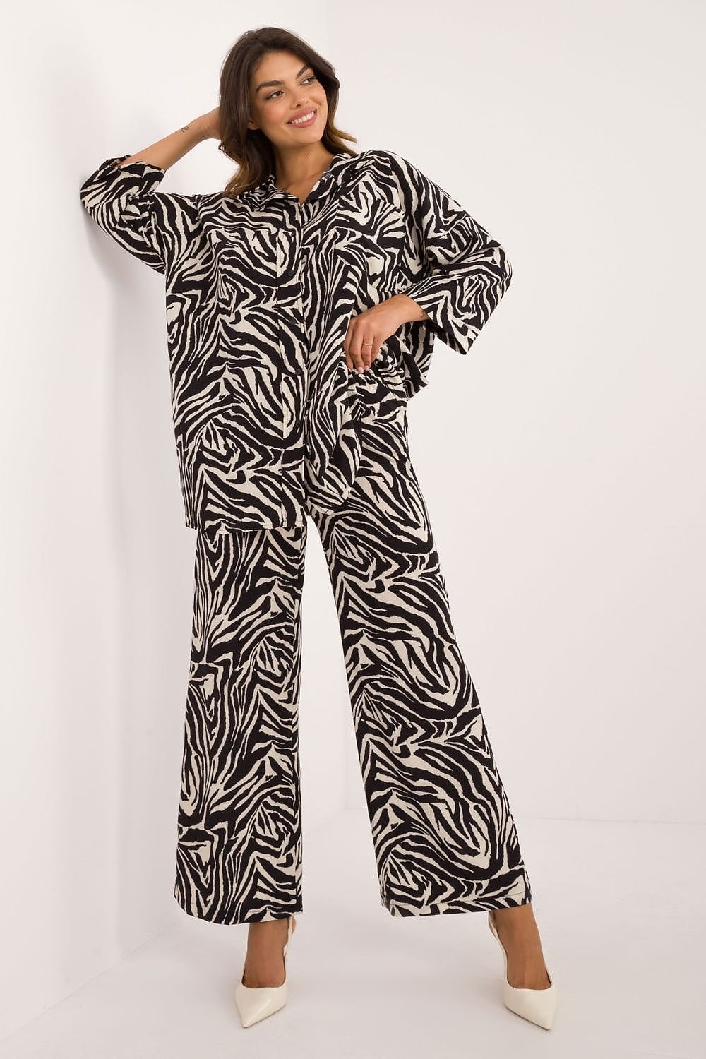 Blije vrouw draagt een modieuze dames set met shirt en wijde broek, voorzien van dierenprint en comfortabele pasvorm,voor aanzicht, 