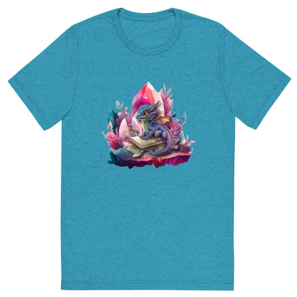 Een aqua triblend unisex T-shirt met een afbeelding van een kleine draak en een magisch boek, op een witte achtergrond