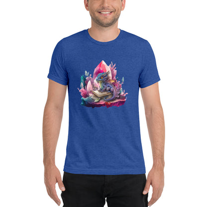 Een True Royal triblend unisex T-shirt met een afbeelding van een kleine draak en een magisch boek, gedragen door een blije man, op een witte achtergrond. De man staat naar voren gericht.